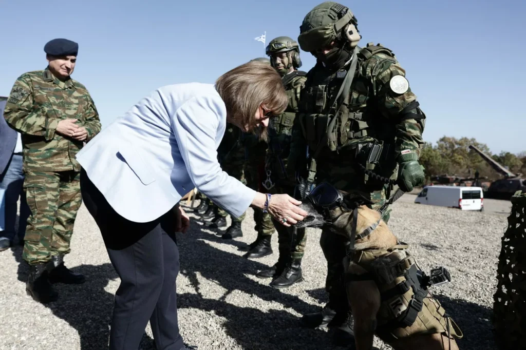 Η Πρόεδρος της Δημοκρατίας Κατερίνα Σακελλαροπούλου, με στρατιωτικό σκύλο της 71 Α/Μ ΤΑΞ στην ΤΑΜΣ ΑΙΣΙΟΣ ΟΙΩΝΟΣ. Εικόνα: Προεδρία της Δημοκρατίας